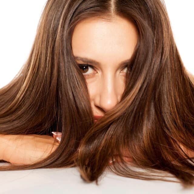 Na zdjęciu przedstawiona jest brunetka przodem, oparta o coś dłońmi.