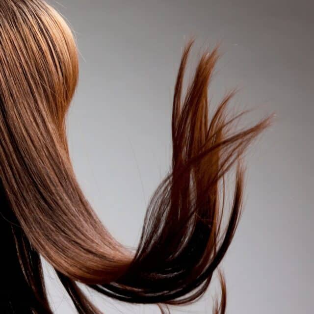 Na zdjęciu przedstawiona jest kobieta od tyłu z długimi, brązowymi włosami.